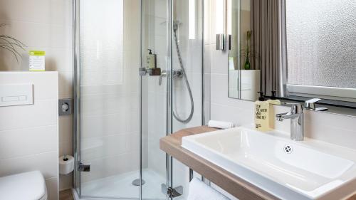 a bathroom with a sink and a shower at Hotel Am Stadtpark in Buxtehude