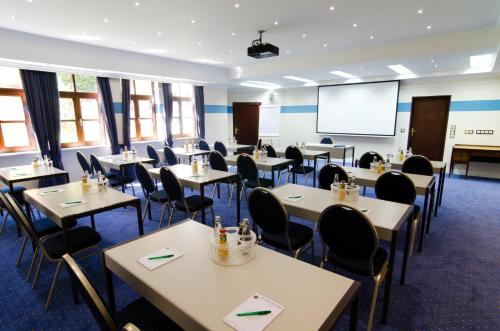 a conference room with tables and chairs and a screen at Schmelmer Hof Hotel & Resort in Bad Aibling
