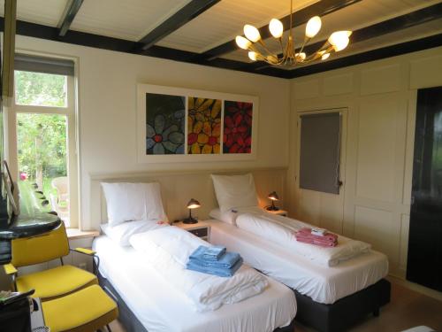 um quarto com 2 camas, uma cadeira e um lustre em B&B Singelstate em Gorredijk