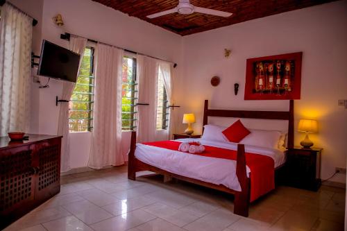 a bedroom with a bed and a tv and a window at Hibiscus House Gambia in Brufut