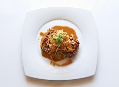 a white plate with a dish of food on a table at Gasthof zur Sonne in Röfingen