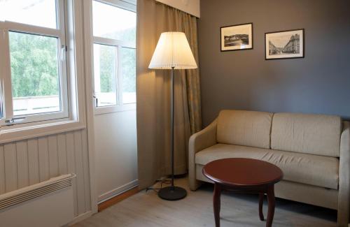 a living room with a couch and a table and a lamp at Best Western Tingvold Park Hotel in Steinkjer