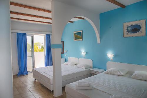 sypialnia z 2 łóżkami i niebieską ścianą w obiekcie Romantza Mare w mieście Kalithea (Rodos)