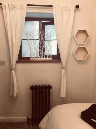 um quarto com uma cama e uma janela com cortinas em Meadfoot Cottage em Torquay
