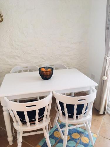 una mesa blanca con dos sillas y un tazón en ella en Meadfoot Cottage, en Torquay