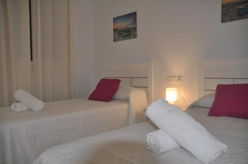 Cette chambre comprend 2 lits avec des oreillers rouges et blancs. dans l'établissement APARTAMENTO ICEBERG TARIFA, à Tarifa