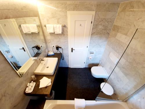 a bathroom with a sink and a toilet and a mirror at Landgasthof "Wilder Mann" in Innsbruck