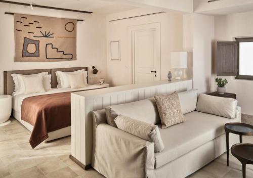 a bedroom with a bed and a couch in front of a bed at Parilio, a Member of Design Hotels in Naousa