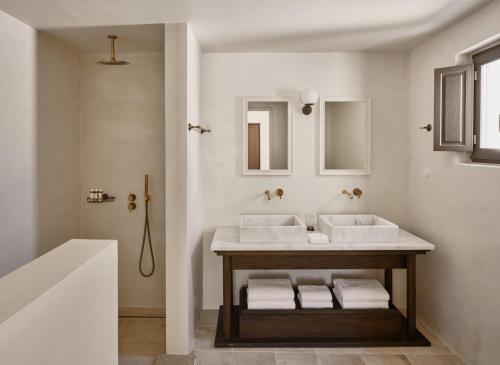 a bathroom with a sink and two mirrors at Parilio, a Member of Design Hotels in Naousa