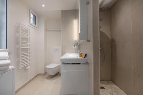 une salle de bain blanche avec des toilettes et un lavabo dans l'établissement Veeve - Crisp Whites in the 16th, à Paris