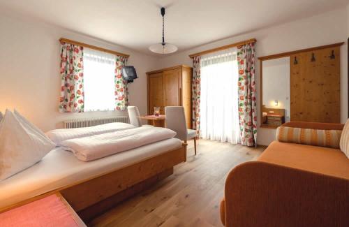 a bedroom with a bed and a couch and windows at Pension Walchauhof in Flachau