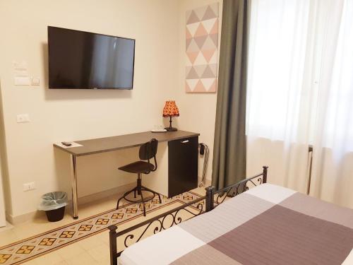 a bedroom with a desk and a television on the wall at B&B Villa Ida Pescara Centro in Pescara