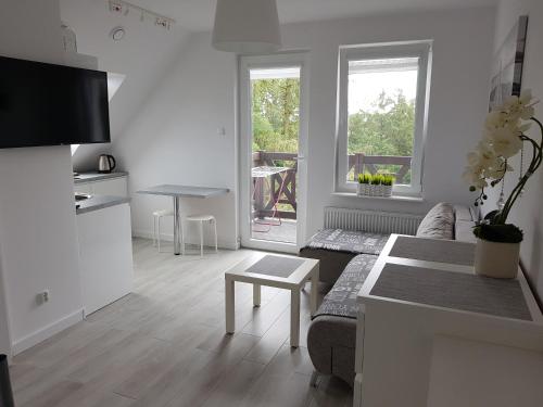 een witte woonkamer met een bank en een tafel bij Sztutowo Apartament Jaś in Sztutowo