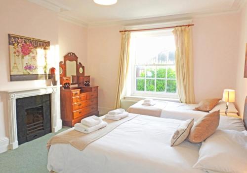 two beds in a room with a fireplace and a window at Bury Villa - 7 bedrooms sleeping 18 guests in Gosport
