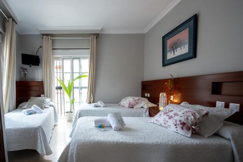 una camera con due letti con lenzuola bianche di Hostal La Muralla a Siviglia
