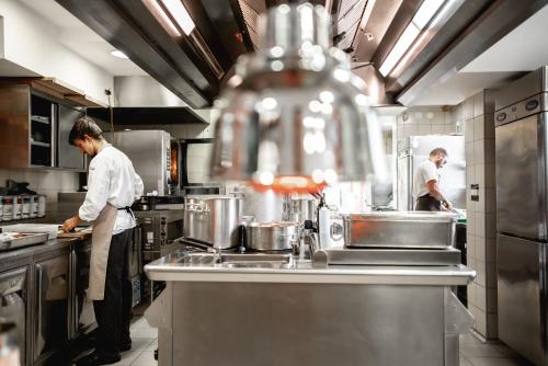 two chefs in a commercial kitchen preparing food at Hotel Dvor Jezersek Brnik in Cerklje na Gorenjskem