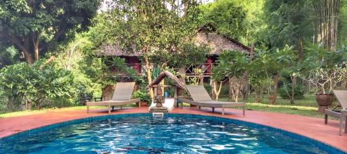 a swimming pool with two chairs in front of a house at Sang Tong Huts in Mae Hong Son