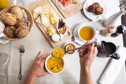 a woman sitting at a table with breakfast food at Hotel Dvor Jezersek Brnik in Cerklje na Gorenjskem