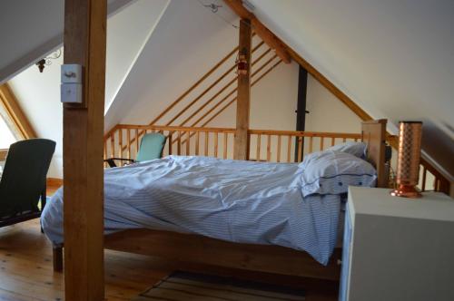 een slaapkamer met een bed en 2 stoelen op een zolder bij Barrington Barn in Barrington