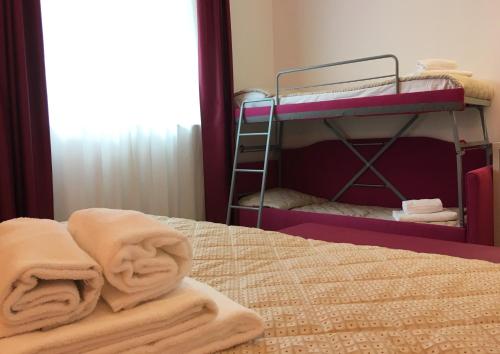 a bed with two bunk beds with towels on it at Alma Living Hotel- Al Girarrosto in Venzone