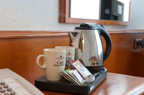 a coffee maker and two cups on a table at Hotel Am Stadtpark in Buxtehude