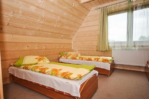 a bedroom with two beds in a wooden room at Domki u Wilka in Poronin