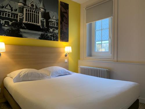 um quarto com uma grande cama branca e uma janela em Hôtel de la Gare - Restaurant Bistro Quai em La Roche-sur-Yon