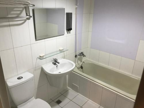 a bathroom with a sink and a toilet and a tub at Long Siang Hotel in Kaohsiung