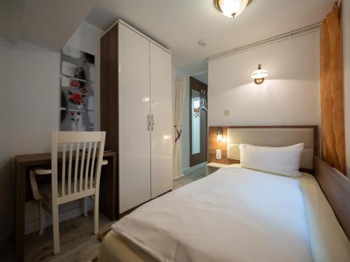ein Schlafzimmer mit einem weißen Bett und einem Stuhl in der Unterkunft Hotel Boritzka in Hamburg