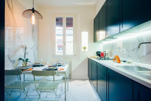 a kitchen with blue cabinets and a table with chairs at Luxury Apartment in Palazzo Spada in Bologna