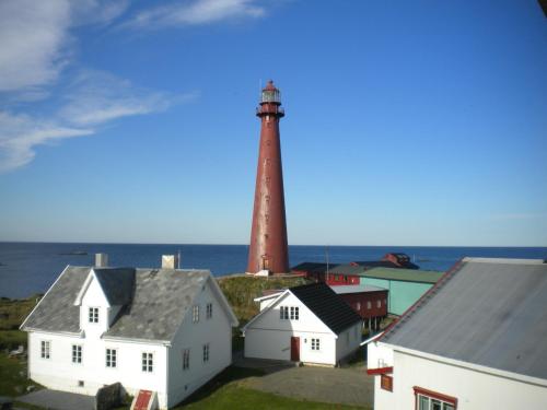 a lighthouse in a town with houses and the ocean at Apt 201 - Andenes Whale Safari Apartments in Andenes