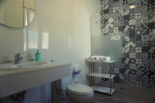 a bathroom with a sink and a toilet and a mirror at Apartamentos Ondeanos in La Carolina