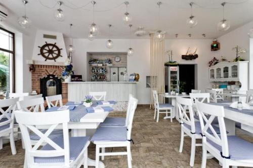 a dining room with white tables and white chairs at Willa Rejs in Krynica Morska
