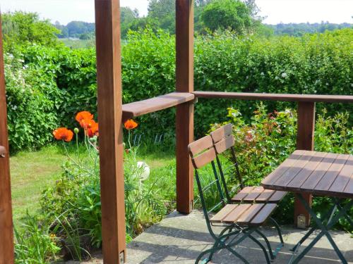 a table and a chair on a porch with flowers at Hotel Kranichblick in Kluis