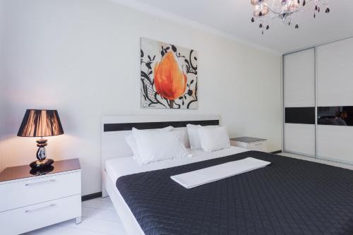 a white bedroom with a large bed and a lamp at Partner Guest House in Kyiv