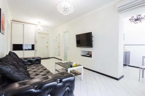 a living room with a leather couch and a tv at Partner Guest House in Kyiv