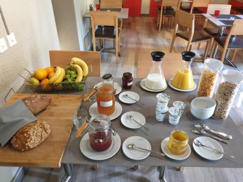 a table topped with plates of food and a basket of fruit at Hôtel du Cygne in Bevaix