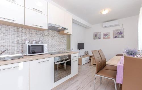 a kitchen with white cabinets and a table with chairs at House Lavander in Šmrika