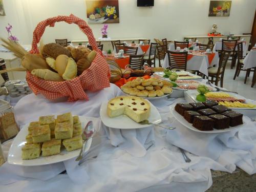 グアラプアバにあるHotel Dom Baroniのいくつかの皿に盛られた食べ物とバスケットが置かれたテーブル