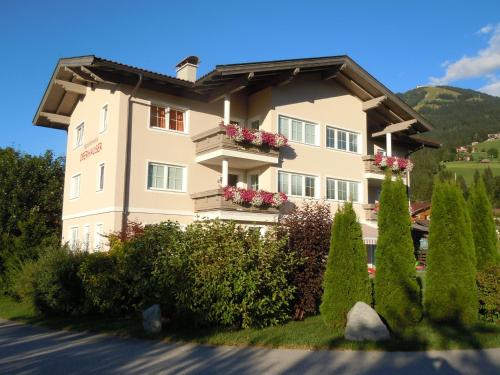 a building with flowers on the balconies and bushes at Appartements Oberhauser in Westendorf