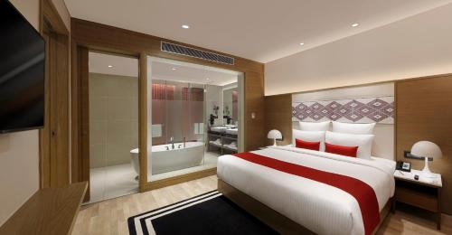 a bedroom with a large bed and a bathroom at Novotel Guwahati GS Road in Guwahati
