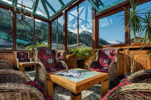 a conservatory with a table and chairs and windows at Hotel Höhlenstein in Tux