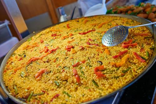 a pan of food with a spatula on top of it at Hotel Don Miguel Playa in Playa de Palma
