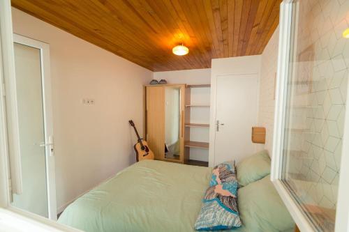 - une petite chambre avec un lit et une guitare dans l'établissement HOSSEGOR LE GARDEN lac et océan à pieds, à Soorts-Hossegor