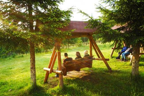 a group of people sitting on a swing in a park at Hotel Floare de Colt in Mănăstirea Humorului