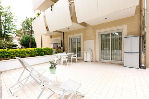 a patio with two white chairs and a table at Aparthotel England in Riccione