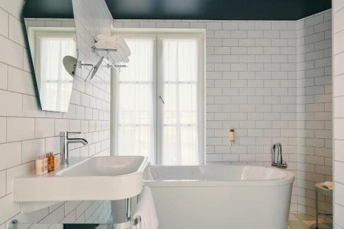 a white bathroom with a tub and a sink at Mercure Marseille Canebière Vieux-Port in Marseille