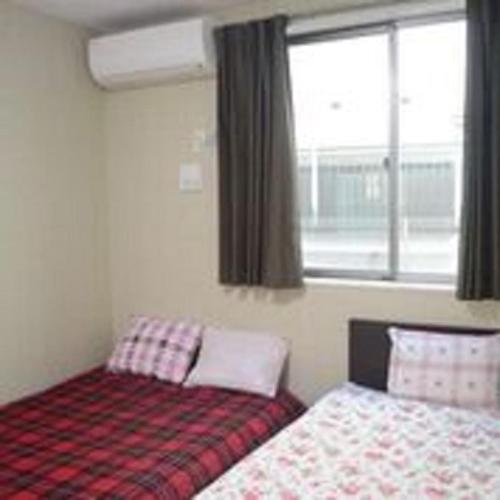 a bedroom with two beds and a window at Tokyo Guest House 2020 in Tokyo
