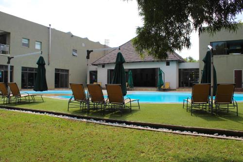 a group of chairs and umbrellas next to a pool at Umuzi Lodge in Secunda