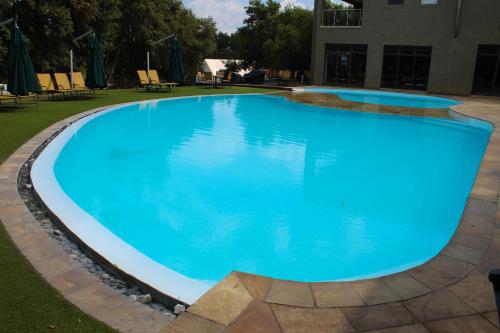 a large swimming pool with blue water at Umuzi Lodge in Secunda